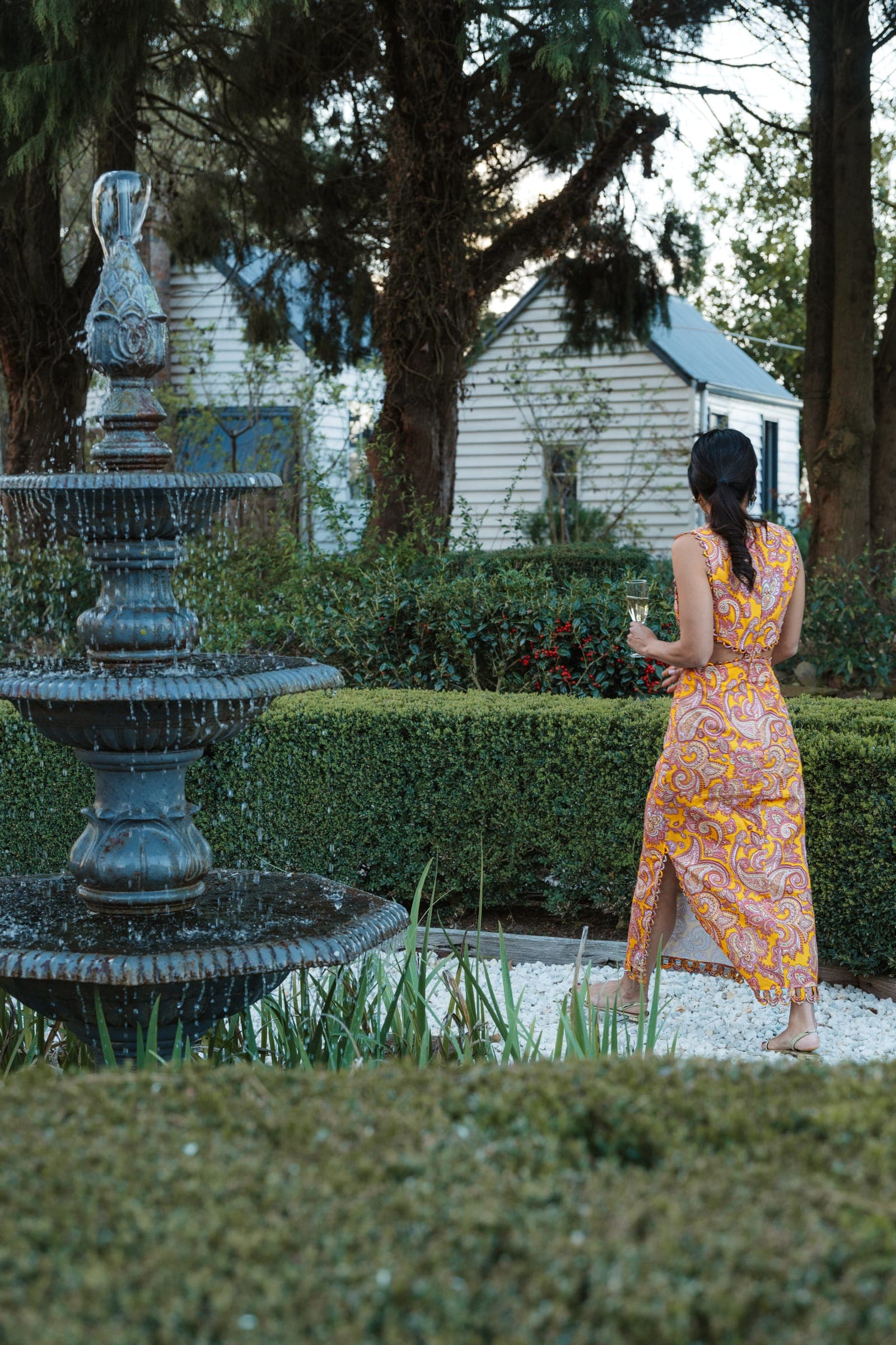 A guest walking past the fountain toward the farmhouse