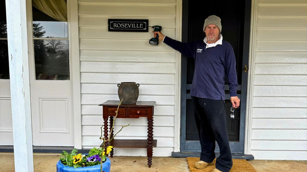 Putting up a welcome to roseville sign on a country farm house